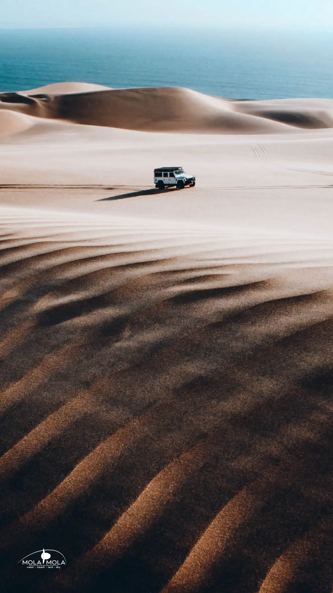 4x4 on dune patterns with ocean backdrop